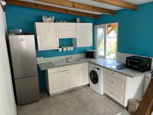 eine Küche mit weißen Schränken und einer blauen Wand in der Unterkunft Le cottage de Port Blanc-Gosier in Le Gosier