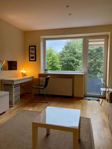 a living room with a desk and a large window at Smelte Studio Apartment in Klaipėda