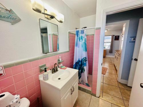 a bathroom with a sink and a pink tile wall at Blue Water Beachside villa 2 in Clearwater Beach