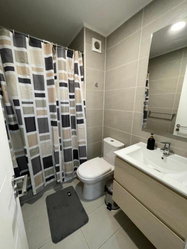 een badkamer met een toilet, een wastafel en een spiegel bij Estilo y comodidad in Concepción