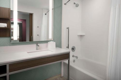 a bathroom with a sink and a mirror and a shower at Hilton Garden Inn Pensacola Downtown in Pensacola