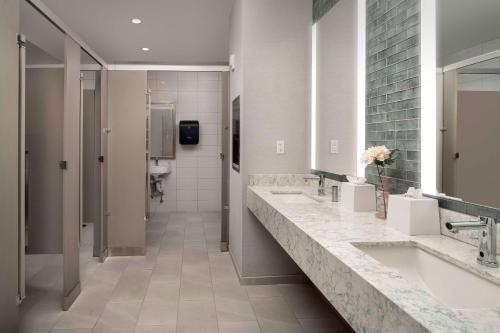 a bathroom with two sinks and two mirrors at Hilton Garden Inn Pensacola Downtown in Pensacola