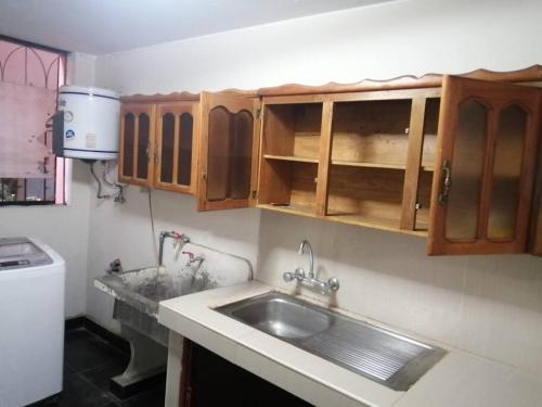 una cocina con fregadero y armarios de madera en Departamento Completo Zona residencial la Molina, en Lima