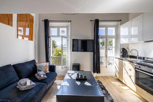 un salon avec un canapé bleu et une cuisine dans l'établissement Quiet apartment - parking and secure residence, à Cannes