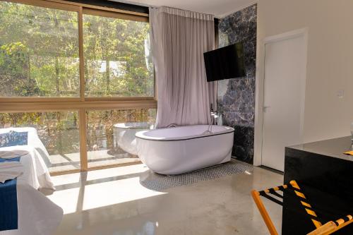 a bathroom with a tub and a large window at Ecolounge Studios in Pirenópolis