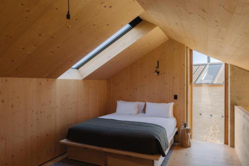Cama en habitación de madera con ventana en Jacks Point - Earth House, en Frankton