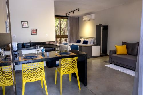 a kitchen and living room with yellow chairs at Ecolounge Studios in Pirenópolis
