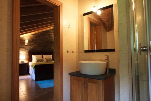 ein Bad mit einem Waschbecken und ein Bett in einem Zimmer in der Unterkunft Casinhas do Ceira in Ponte de Fajão