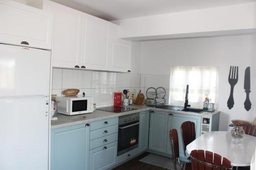 a kitchen with white cabinets and a table with a microwave at Casa do Cabeço in Proença-a-Nova