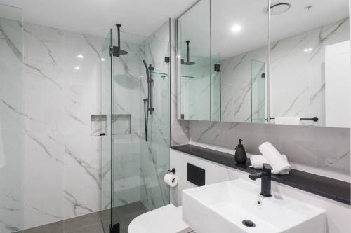 a white bathroom with a sink and a shower at 'Wollongong Inner-city Escape' Bright Urban Oasis in Wollongong