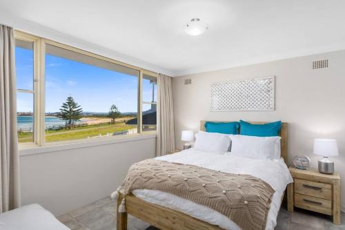 a bedroom with a bed and a large window at Seaside Escape - Stunning Vistas over Towradgi Beach in Wollongong