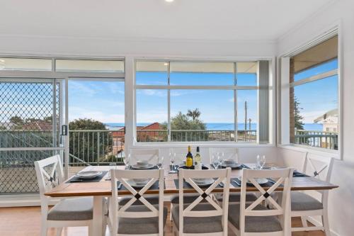 a dining room with a table and chairs and windows at Harbourview Escape - Serene Shellharbour Family Stay in Shellharbour