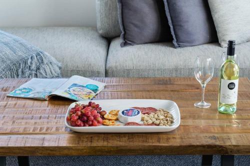 a tray of food on a table with a bottle of wine at Harbourview Escape - Serene Shellharbour Family Stay in Shellharbour