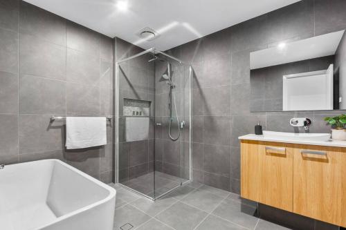 La salle de bains est pourvue d'une douche, d'un lavabo et d'une baignoire. dans l'établissement East Corrimal Escape - Beautiful Beachside Living, à Bellambi