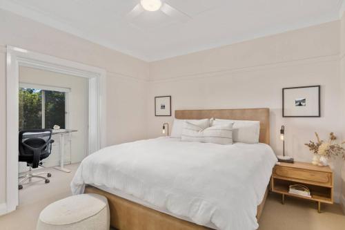 ein weißes Schlafzimmer mit einem großen Bett und einem Schreibtisch in der Unterkunft Annie's Escape - Elegant Coastal Style by the Beach in Wollongong