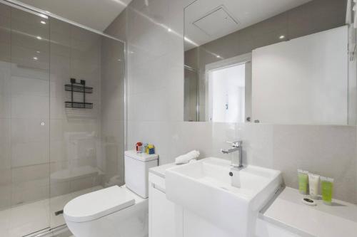 La salle de bains blanche est pourvue de toilettes et d'un lavabo. dans l'établissement Bonbeach Bliss - Contemporary Waterfront Living, à Bonbeach