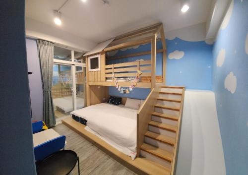 Ce lit superposé se trouve dans un dortoir doté d'un mur bleu. dans l'établissement The Railroad Runs, à Taïtung