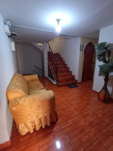 ein Wohnzimmer mit einem Sofa und einer Treppe in der Unterkunft Hostal Los Andes, Cerro Colorado , Arequipa in Zamacola