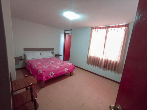 1 dormitorio con cama rosa y ventana en Hostal Los Andes, Cerro Colorado , Arequipa, en Zamacola