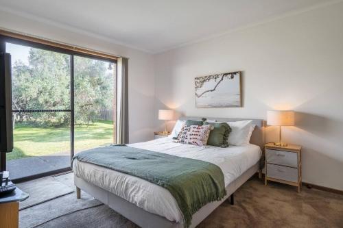 een slaapkamer met een bed en een groot raam bij Solander's Retro Residence - By the Beach Group Stay in Dromana