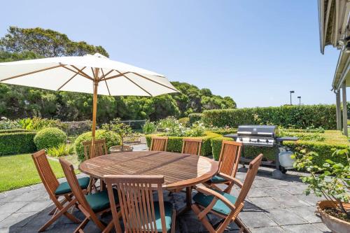 a wooden table with chairs and an umbrella at Viewbank Homestead - A Sprawling Garden Estate in Shoreham