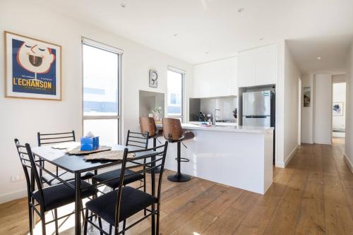 a kitchen and dining room with a table and chairs at 'Tides and Treasures' Unveil a Bonbeach Beachfront Bliss in Melbourne