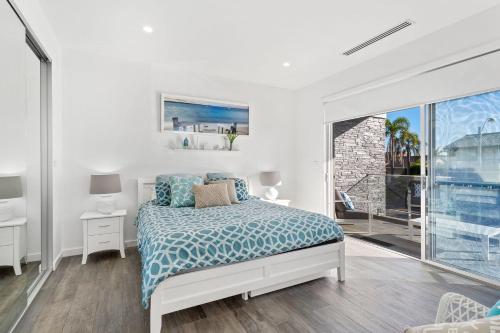 Dormitorio blanco con cama y ventana grande en Bluewater Splendour - Heated infinity pool and amazing views!! en Salamander Bay
