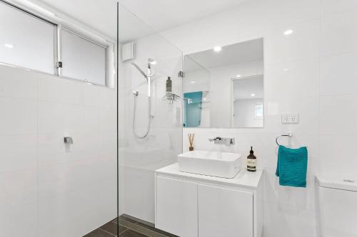 a white bathroom with a sink and a shower at Bluewater Splendour - Heated infinity pool and amazing views!! in Salamander Bay