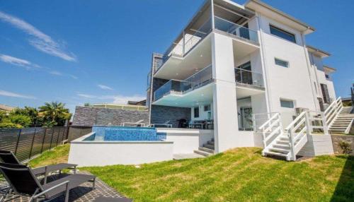 a large white house with a swimming pool at Bluewater Splendour - Heated infinity pool and amazing views!! in Salamander Bay