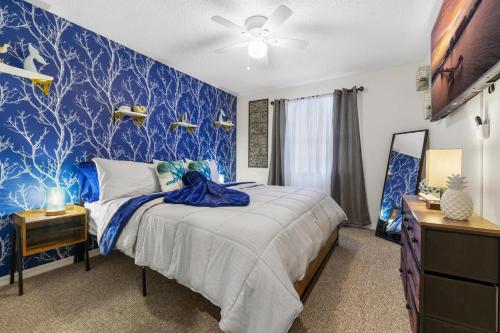 een slaapkamer met een bed met een blauwe muur bij Ultimate Beach Getaway · Mins from Beach · Hot Tub · Heated Pool · Game Room in Seminole