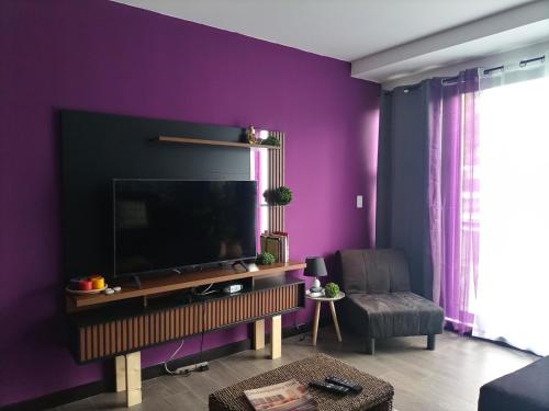 sala de estar con TV y pared púrpura en Suite Zen en Guatemala