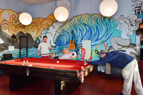 a man playing pool in front of a mural at La Casona de Lobitos - Cowork in Lobitos