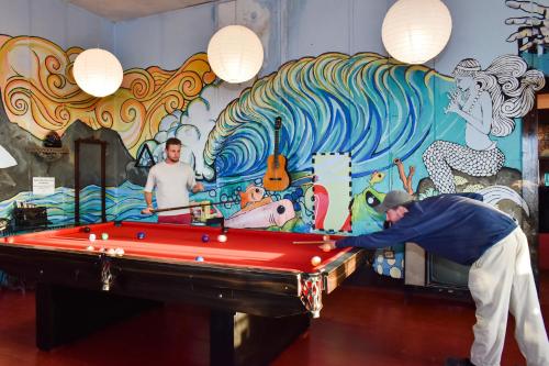 un hombre jugando al billar delante de un mural en La Casona de Lobitos - Cowork, en Lobitos