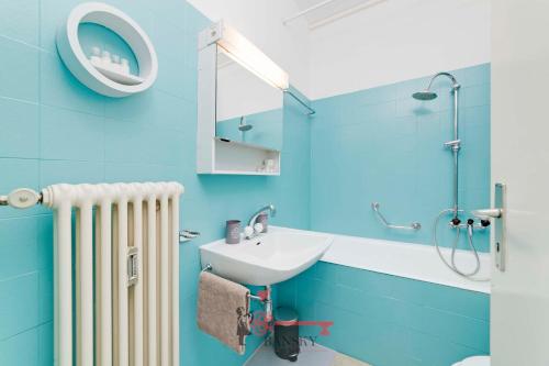 une salle de bains bleue avec lavabo et radiateur dans l'établissement Lime Splendido x4PAX Lugano City, à Lugano