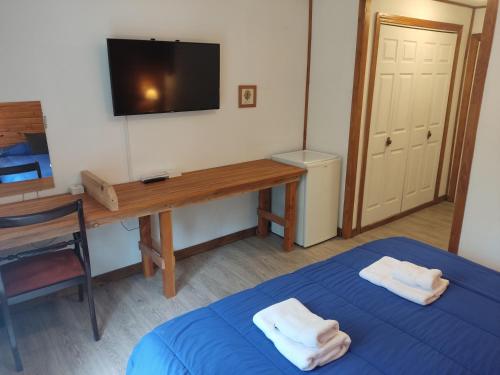 a room with a bed and a desk and a television at Hosteria Lekun Lekun in Villa La Angostura