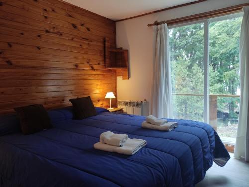 Un dormitorio con una gran cama azul con toallas. en Hosteria Lekun Lekun en Villa La Angostura
