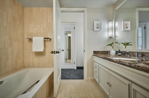 a bathroom with a tub and a sink and a mirror at Pendry Newport Beach in Newport Beach