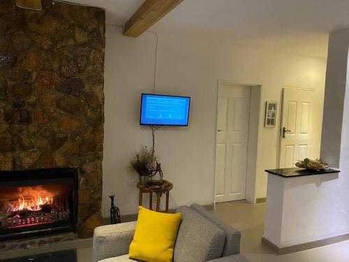 a living room with a fireplace and a tv on a wall at Msasa Views Cottage in Juliasdale