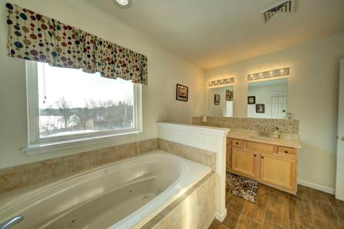 baño con bañera, lavabo y ventana en Stunning Lakefront Home - Swim, Fish, Kayak, HotTub, en Long Pond