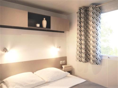 a bedroom with a bed and a window with a window at Camping Carabasse Vias plage. in Vias