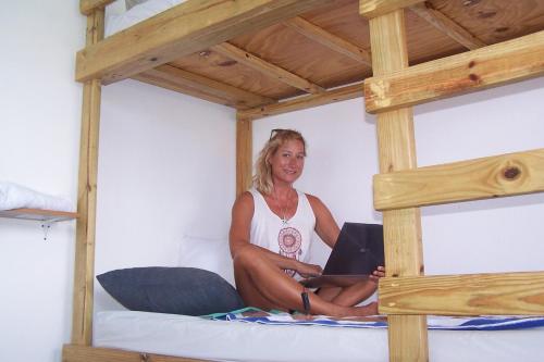 a woman sitting on a bunk bed with a laptop at Shrimpy's Hostel, Crew Quarters and Laundry Services in Marigot