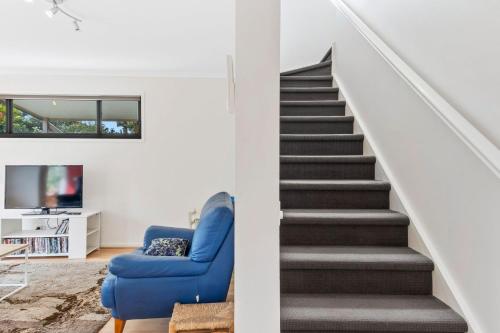 a staircase in a house with a blue couch and a blue chair at Cape Irvine in Cape Paterson
