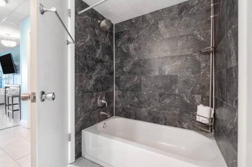 a bath tub in a bathroom with a black wall at Slice o’ Paradise - Gulf Front! Walk to Pier Park in Panama City Beach