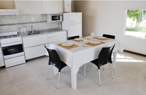 a kitchen with a white table and black chairs at Mi Calma in Yatay