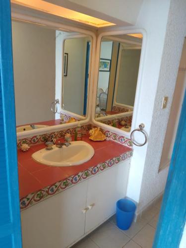 baño con lavabo y 2 espejos en Departamento en Acapulco La Palapa, en Acapulco