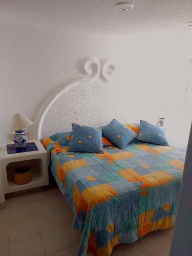 Un dormitorio con una cama con almohadas azules. en Departamento en Acapulco La Palapa, en Acapulco