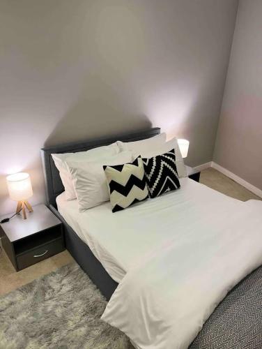 Una cama con almohadas blancas y negras. en Modern Room with Private Bathroom, en Croydon