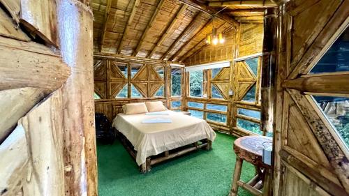 ein Schlafzimmer mit einem Bett in einem Holzhaus in der Unterkunft Hostería El Sendero - Cocorná in Cocorná