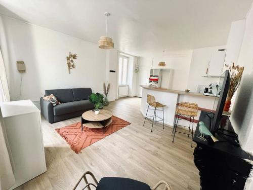 ein Wohnzimmer mit einem Sofa und einem Tisch sowie eine Küche in der Unterkunft La Cornaline in Vesoul