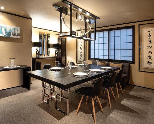 une salle à manger avec une grande table et des chaises noires dans l'établissement Hakuba Mountain Lodge, à Hakuba